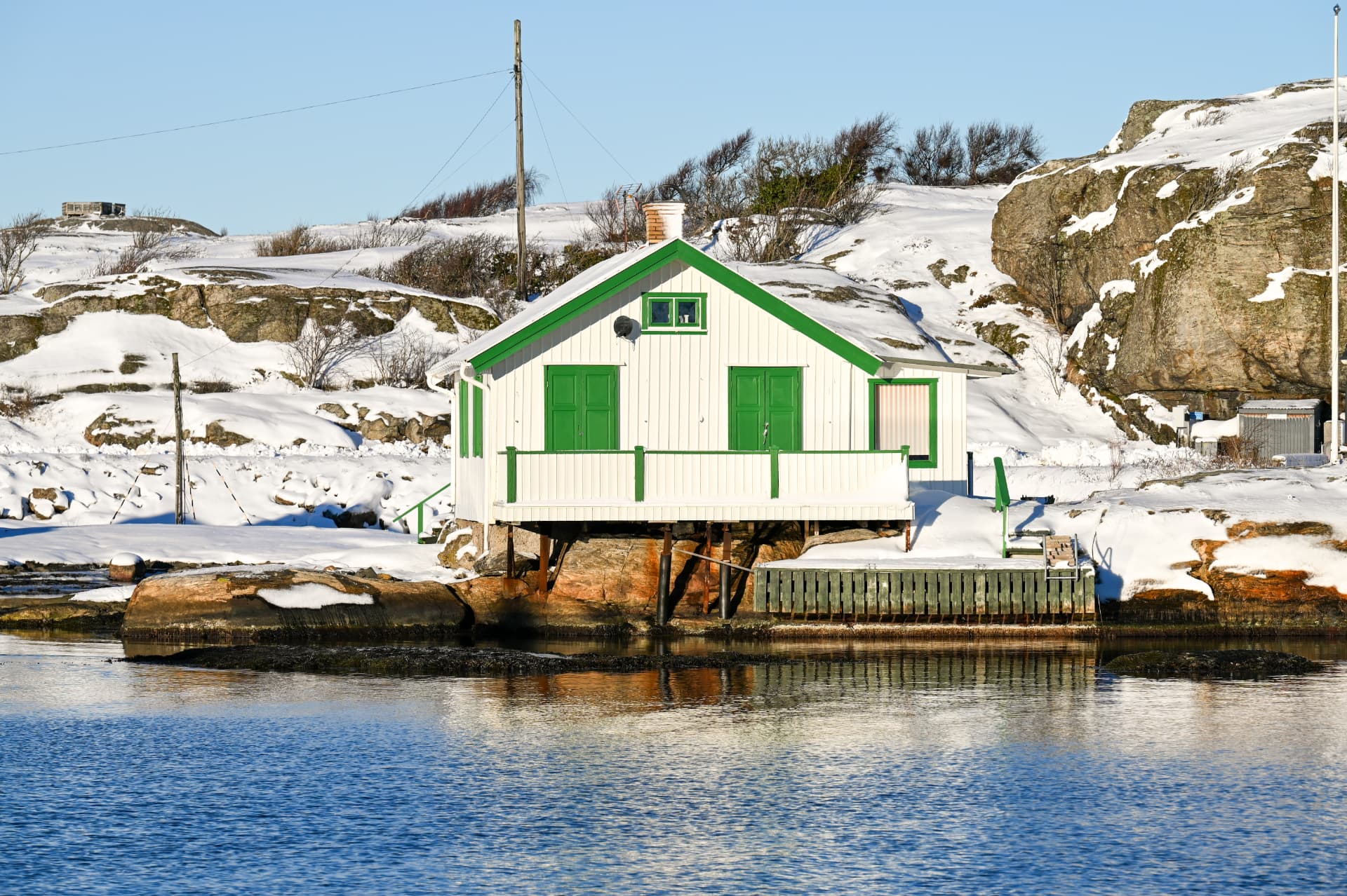 Vit sjöbod vid vattnet på Marstrand
